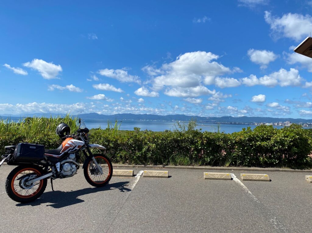 オレンジのツーリングセローと桜島から見る鹿児島市